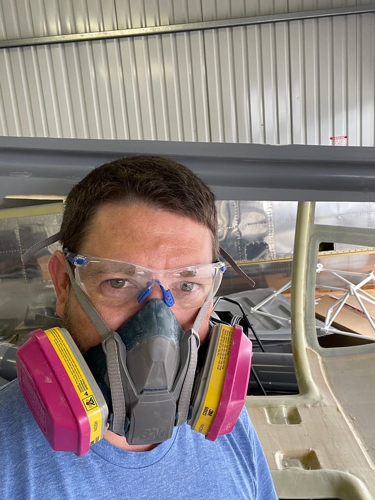 Wearing a respirator to protect from fiberglass dust. 